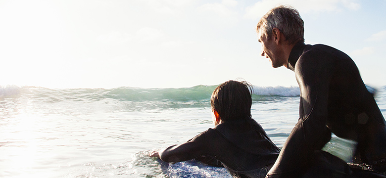 A father and son surfing on a sunny day